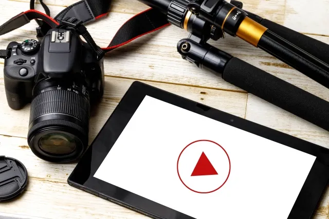 一眼レフカメラと三脚、白い再生マークが表示されたタブレット